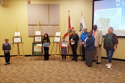 Arbor Day Poster Contest Winners Zion Broadway (left), Lily Lakatani, and Kaylee Riggins stand with City of Sanford Urban Forester Elizabeth Harkey, Mayor Art Woodruff, and Commissioners Sheena Britton, Kerry Wiggins, Sr., and Patty Mahany at Monday’s commission meeting.