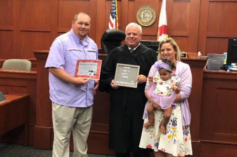 Officer Zach Glenn (left) with the judge and wife Sabrina (right) and adopted daughter. 