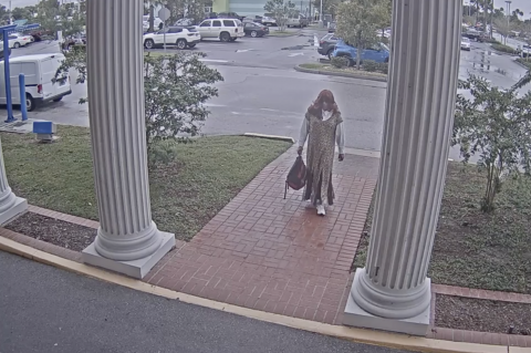Video shows Reyes walking into the bank with a dress and wig on and holding his backpack. 