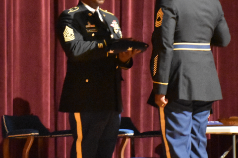 Ret. Command Sergeant Major Gregory Jackson receives U.S. flag during retirement ceremony from Master Sergeant David Brooks who served as soldier under Jackson 17 years ago. 