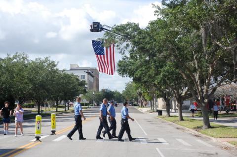 Local firefighters arrive Monday morning for Memorial Day Remembrance Ceremony as a ladder truck displays the American flag over Park Avenue in front of Sanford City Hall.