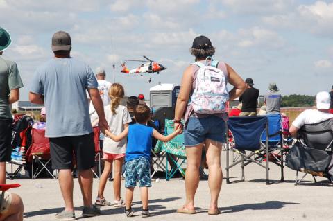 A family watches a U.S. Coast Guard helicopter simulate a sea rescue on the runway at the Sanford airport on Saturday.