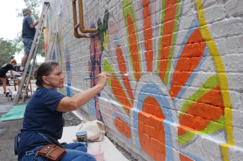 Artist Elisabeth Ferber of Mount Dora works on a ground level spot of the Hotchkiss Building mural Friday morning.