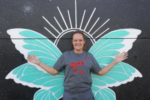 Robin Block, a server at Shantell’s Just Until café on Sanford Avenue, stands in front of a pair of wings.