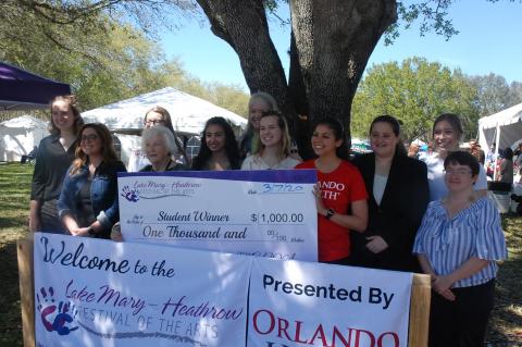 A group of students along with members of the Lake Mary-Heathrow Festival of the Arts Board stand with one of the scholarship checks presented to the students last weekend.
