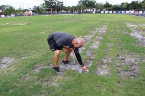 Seminole High School Athletic Director Michael Kintz examines the worn-down football field, which they want to raise $1 million to fix up.