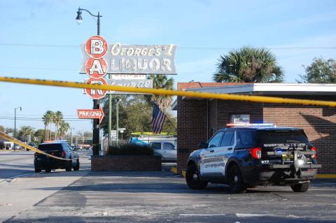 Sanford police cars sit behind crime scene tape at George’s Tavern on Thursday morning after a carjacker was shot and killed. 