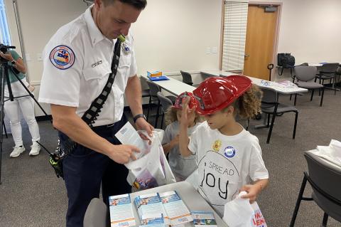 SCFD Lt. Anthony Bowman (left) gives drowning prevention resource packets to children at the event.