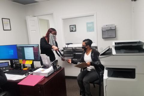 LIHEAP Program Supervisor Maria Garcia (left) assists her first client in the Casselberry office, Trenece Butler (right). 
