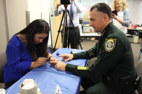 Sheriff Dennis Lemma gets his fingernails painted for the MANicure Movement on Thursday, symbolizing awareness of child abuse.