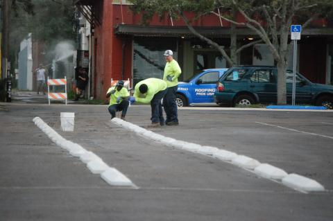 Crews work at the parking lot at the northeast corner of 1st Street and Palmetto Avenue to lay out markers for parking spaces.