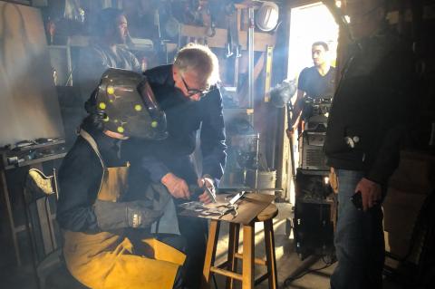 Artist and Welder Kevin Abbott (center) shows an actress proper welding techniques while Filmmaker Kevin O’Neill (right) directs the action.
