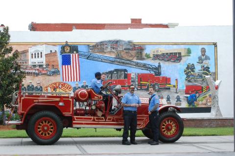 Members of the Sanford Fire Department (right) admire the mural and show off Sanford’s antique fire engine (below) during the ribbon cutting ceremonty on Thursday. 