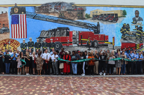 City officials, members of the Sanford Fire Department and the public gather Thursday afternoon to celebrate the ribbon cutting for the mural in Paulucci Park celebrating the Fire Department’s 150th anniversary.