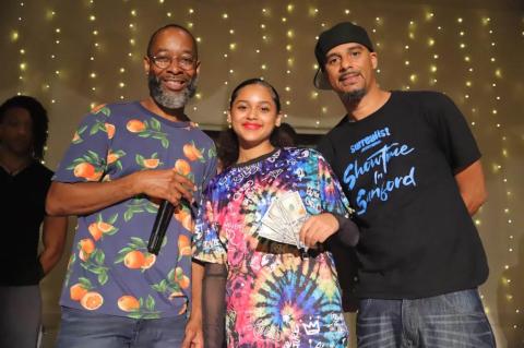 Host Jay Love, left, and Surrealist Entertainment CEO Lawrence Gordon, right, pose with Latalya Burns, a Millennium Middle School student, who collects the $500 first prize on behalf of her dance team partner, Caelin de Guzman. The pair won a close competition at Thursday’s Showtime in Sanford.