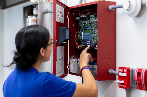 A Seminole State student works on a fire sprinkler system panel.