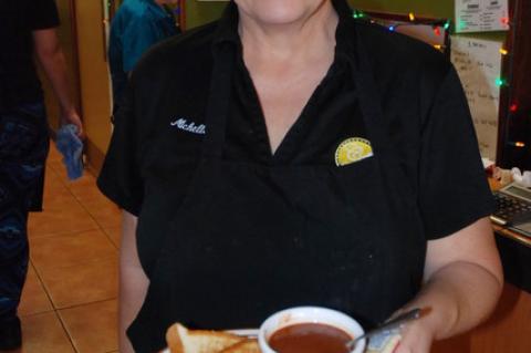 Colonial Room owner Michelle Simoneaux presents a grilled cheese special with tomato basil soup made by Second Harvest Food Bank culinary students.